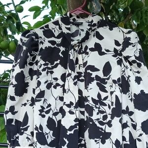 Beige blouse with black roses splattered throughout. The neck has enough slack..